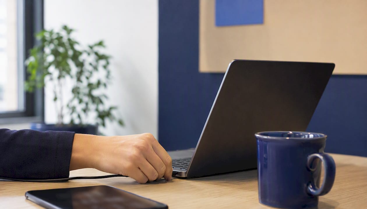 Une main branche le chargeur sur l’ordinateur portable.