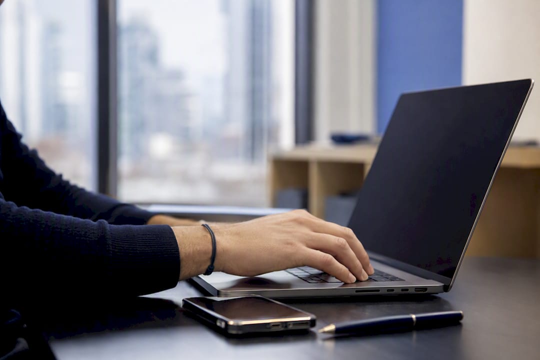Main interagissant avec le clavier d’un ordinateur portable